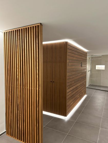 Holzvertäfelte Duschkabine mit moderner Beleuchtung in einem hochwertigen Innenausbau.
