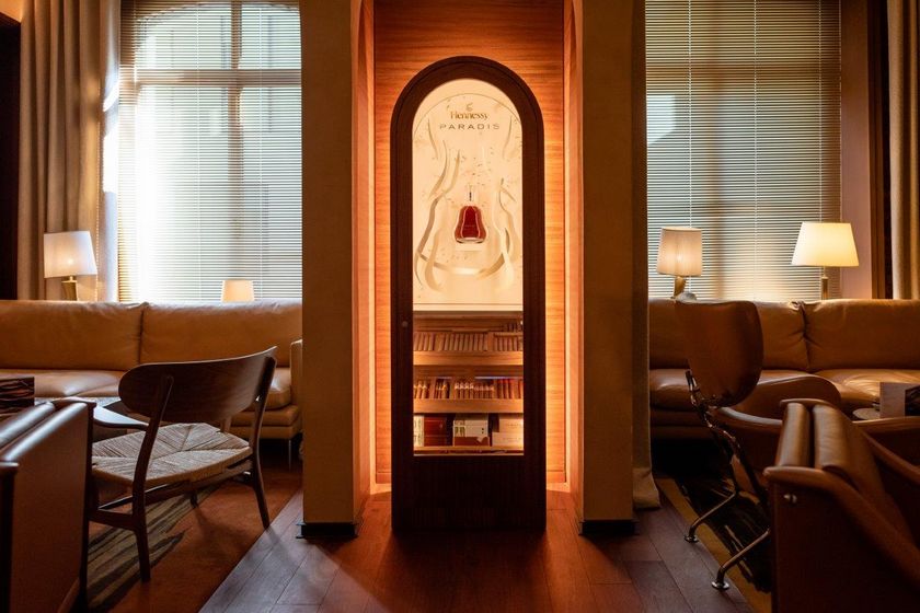 Elegante Lounge mit beleuchtetem Schmuckschrank, umgeben von Ledersesseln.