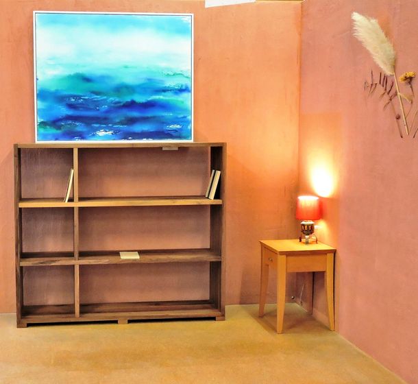 Holzregal und Tisch in gemütlichem Raum mit blauem Wandbild.