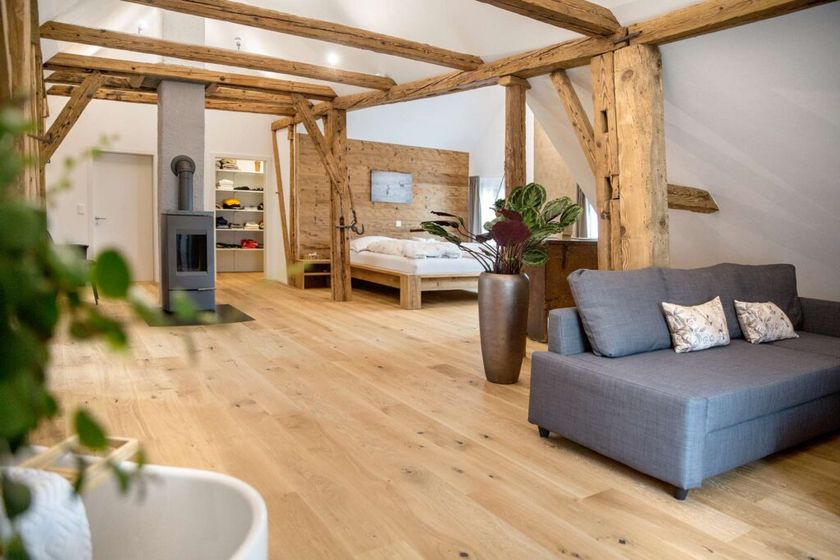 Rustikales Interieur mit Holzbalken, Sofa und Holzfussboden in einem gemütlichen Wohnraum.