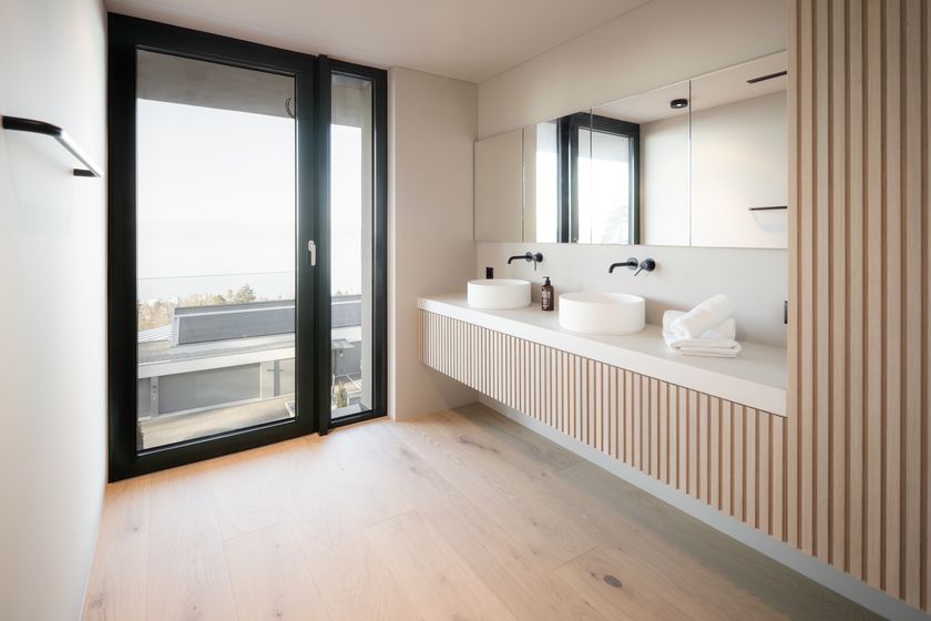 Modernes Badezimmer mit Holzdetails und zwei Waschbecken, mit Blick nach draussen durch ein großes Fenster.