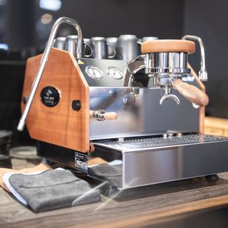 Hochwertige Espressomaschine mit Holzverkleidung auf Holztresen in modernem Innenraum.