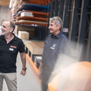 Zwei Männer im Lager der Stark AG mit Holzwerkstoffen im Hintergrund.