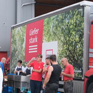 Mitarbeiter von Stark AG beim Pausieren vor einem Lieferwagen mit der Aufschrift 'Liefer stark'.