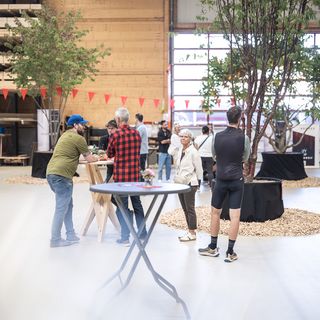 Menschen in moderner Holzausstellungshalle bei informellem Treffen.