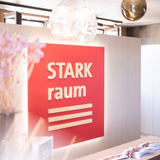 Innenansicht eines modernen Holzhändler-Büros mit rotem Logo an der Wand.