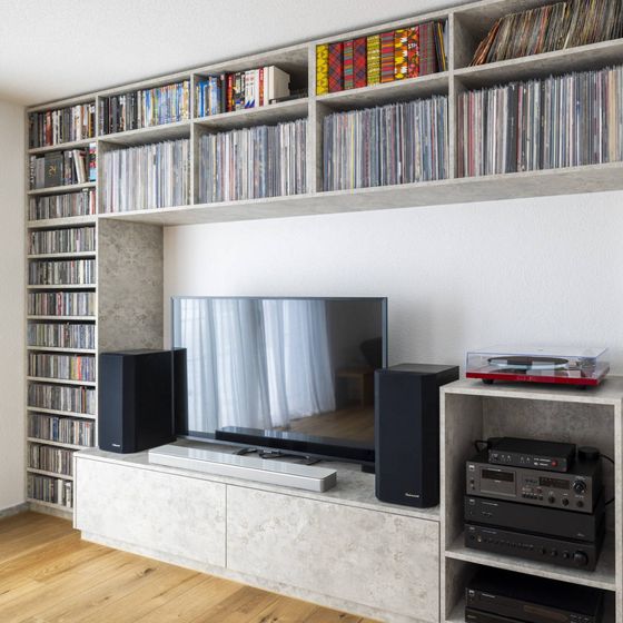 Moderne Wohnwand mit Schallplattensammlung und Unterhaltungselektronik in einem hellen Raum.