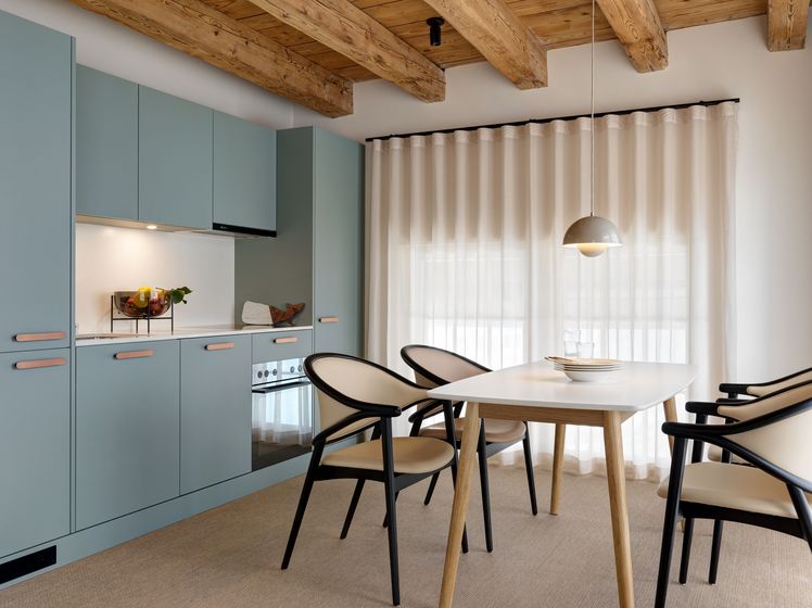 Moderner Essbereich mit Holzelementen und blauen Küchenschränken.