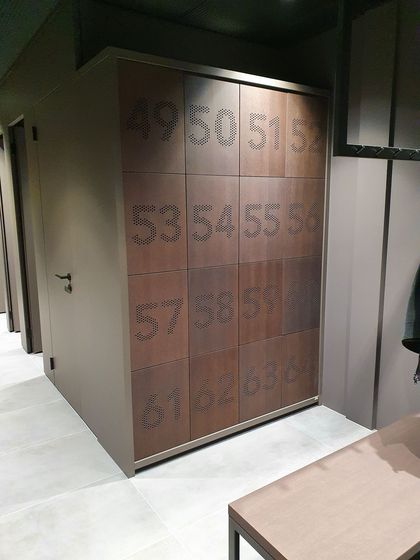 Holzverkleidete Schrankanlage mit nummerierten Türen in einem modernen Raum.