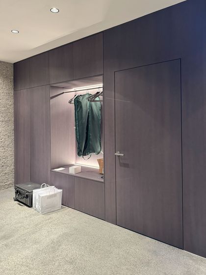 Moderner Einbauschrank in minimalistischem Design mit Kleidung und Taschen.