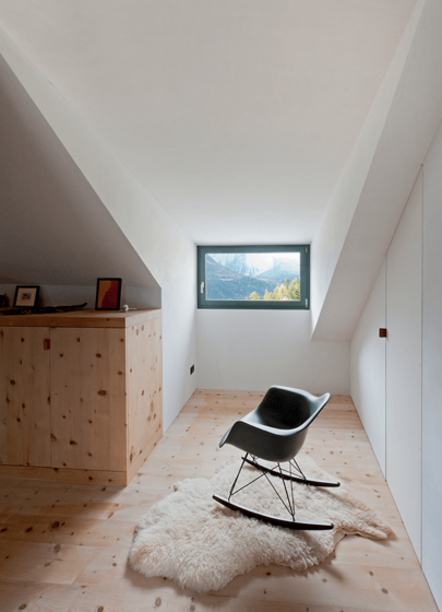 Innenraum mit Schaukelstuhl, Holzfussboden und Bergblick durch Fenster.