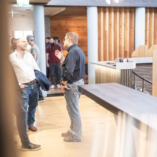 Mehrere Menschen unterhalten sich in einem modernen Ausstellungsraum mit Holzverkleidung bei Stark AG Altstätten.