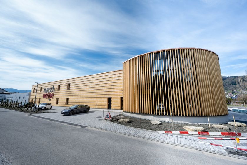 Modernes Holzgebäude mit markanter Fassade und Autos im Vordergrund.