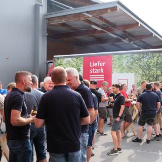 Menschen versammeln sich bei einer Veranstaltung vor einem Stark-Lieferwagen.