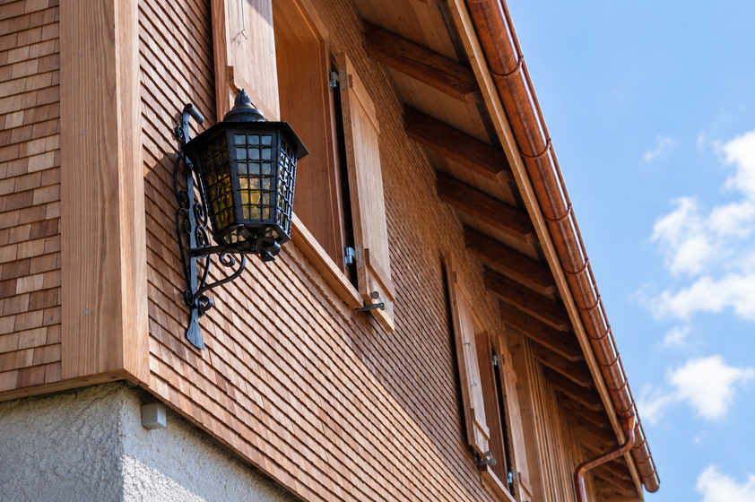 Holzverkleidetes Haus mit Laterne und blauen Himmel im Hintergrund.