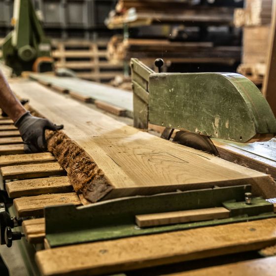 Holzbrett wird an einer Säge bearbeitet.