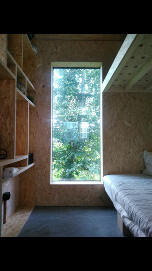 Modernes Innenraumdesign mit Holzwerkstoffen und grossem Fenster mit Blick ins Grüne.