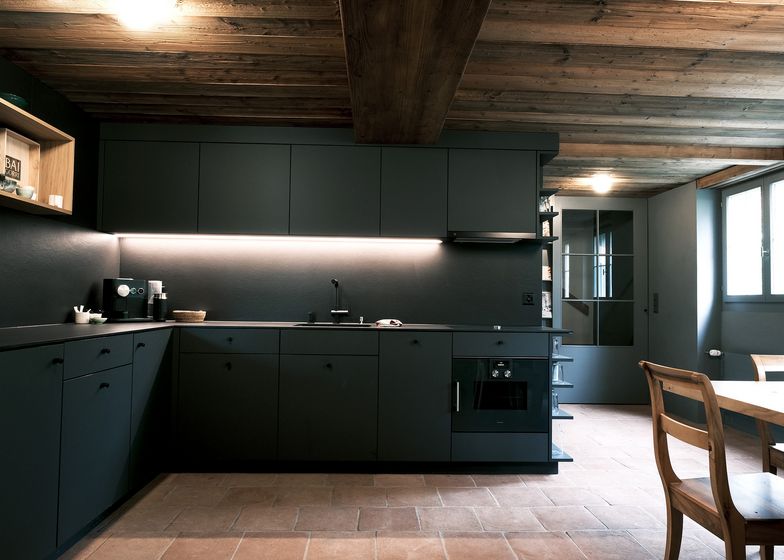 Moderne Küche mit Holzdecke und dunklen Fronten.