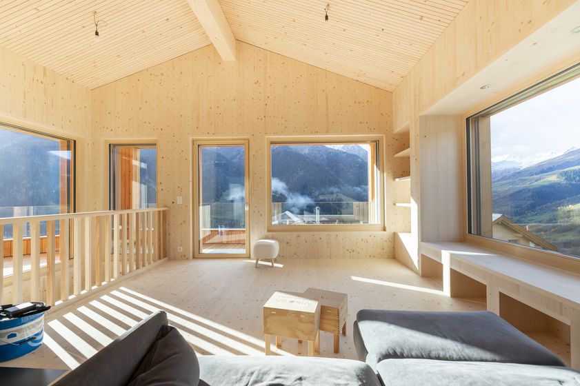 Helles Wohnzimmer mit Holzverkleidung und Panoramablick auf die Berge.