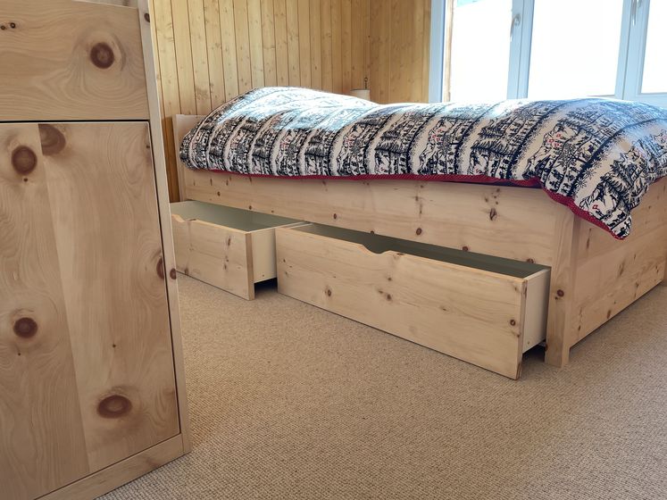 Holzbett mit geöffneten Schubladen in einem gemütlichen Raum.