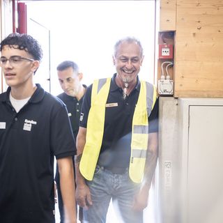 Drei Mitarbeiter der Stark AG Altstätten in Arbeitskleidung betreten einen Raum.