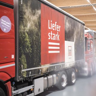 Ein redaktioneller LKW mit Stark-Branding parkt in einer modernen Lagerhalle.