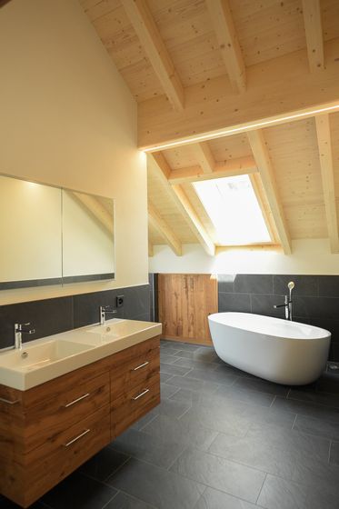 Modernes Badezimmer mit freistehender Badewanne und Holzdekor unter Dachschräge.
