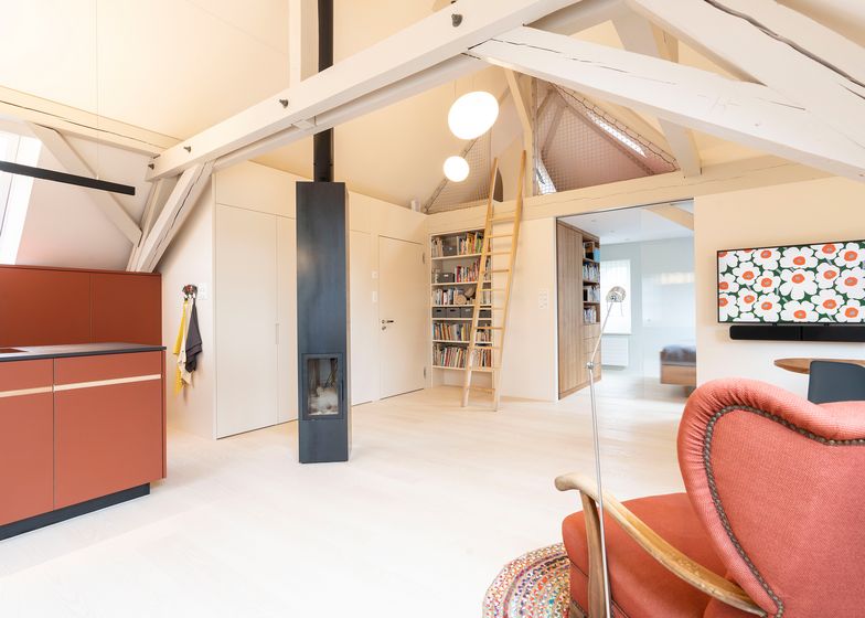 Helles modernes Wohnzimmer mit Holzbalken, offener Küche und Bücherregal.