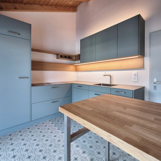 Moderne Küche mit blauen Schränken und Holzarbeitsplatte.