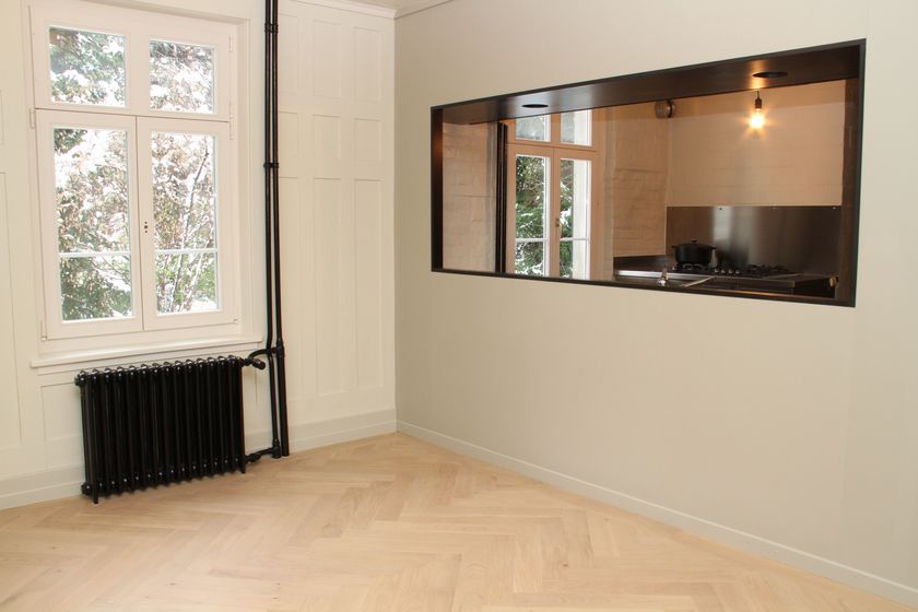 Innenraum mit Fenster und Hartholzboden, der eine moderne und minimalistische Einrichtung zeigt.