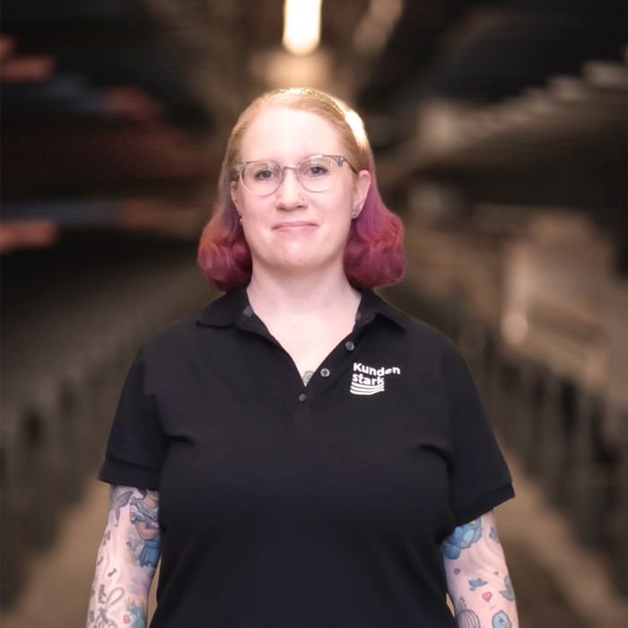 Frau im Stark-AG-Poloshirt steht in einem Lager.