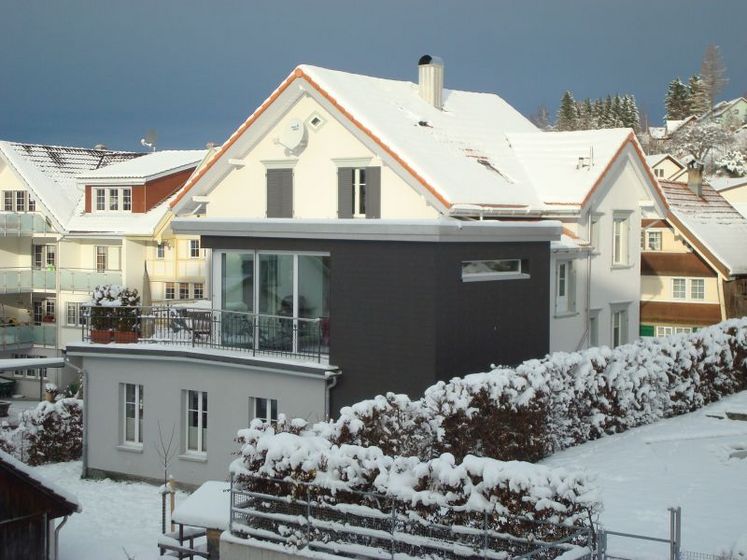Schneebedecktes Haus in Wohngegend mit modernen Akzenten.