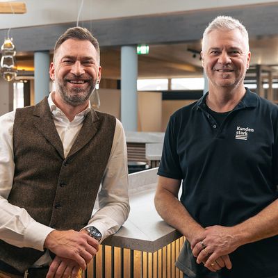 Zwei Männer in einem modernen Innenausbauraum der Stark AG Altstätten lächelnd stehend.