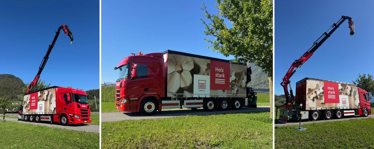 Stark AG LKW Roter Lastwagen der Stark AG mit Kranarm auf einer Landstrasse bei blauem Himmel.