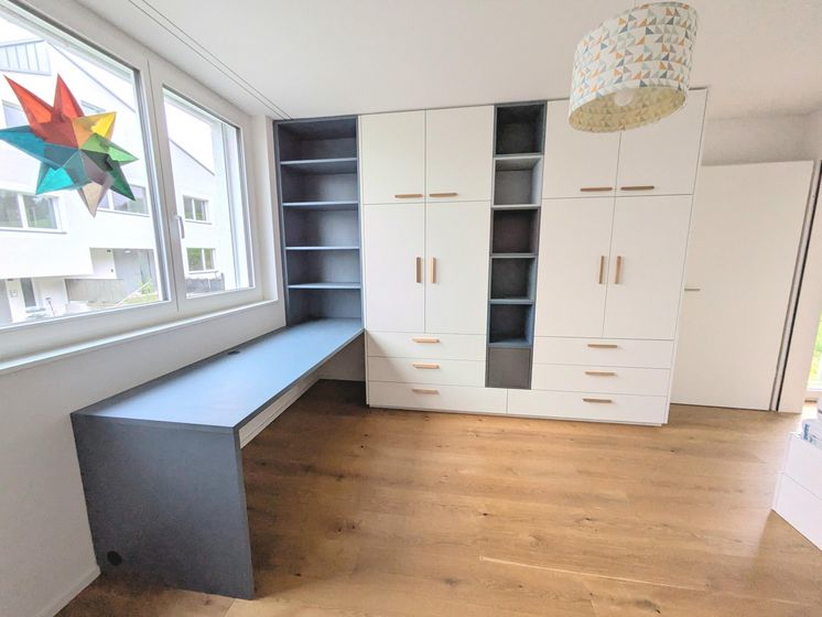 Moderner Einbauschrank und Schreibtisch in einem hellen Raum mit Holzboden.