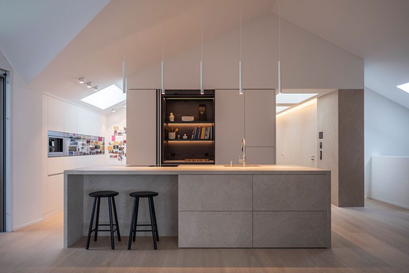 Moderne, minimalistische Küche mit zentralem Inselblock und Hockern in hellem Raum.