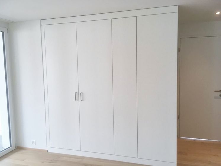 Moderner Einbauschrank aus Holz in einem hellen Raum mit Holzboden.