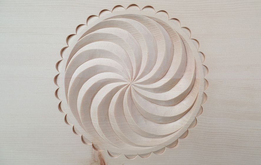 Detaillierte Spiralschnitzerei in hellem Holz.