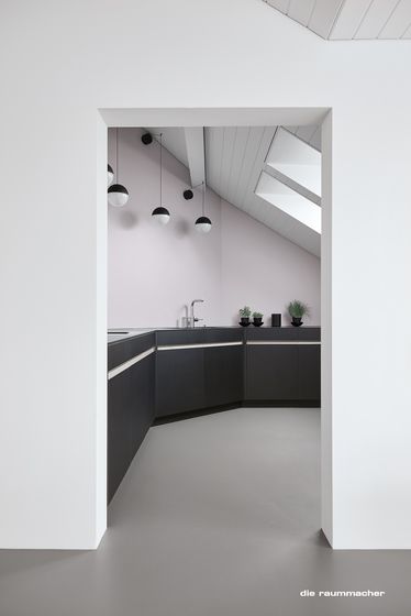 Minimalistische moderne Küche mit schwarzen Schränken und hängenden Kugelleuchten.