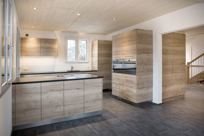 Moderne Küche mit Holzverkleidung und schwarzen Arbeitsplatten in einem offenen Raum.