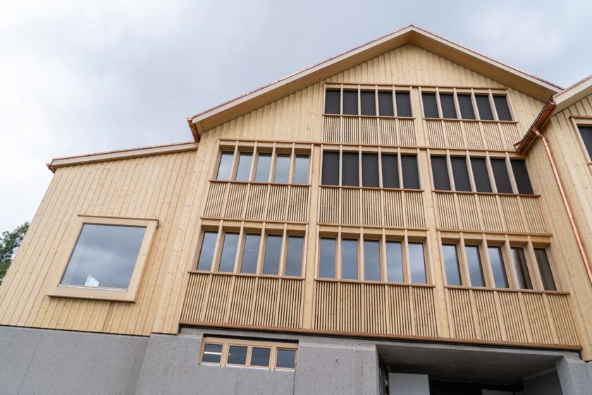 Modernes Gebäude aus Holzwerkstoffen mit grossen Fenstern.
