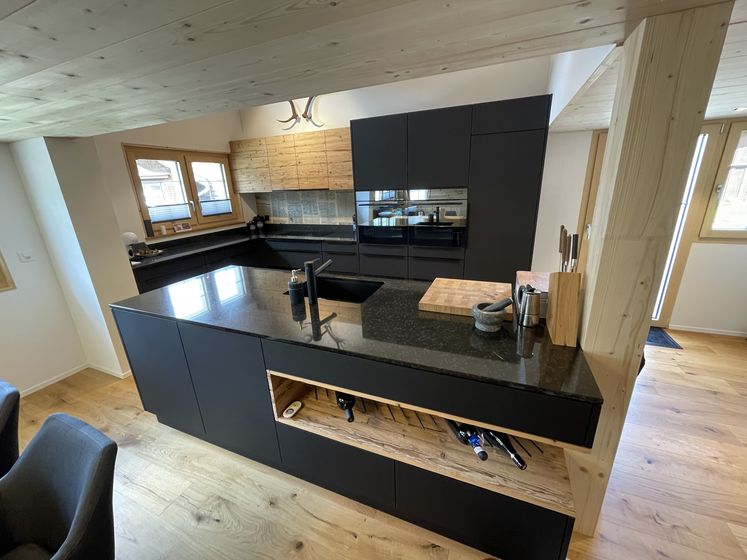 Moderne Küche mit Holz- und Granitoberflächen, ausgestattet mit hochwertigen Geräten und offenem Design.