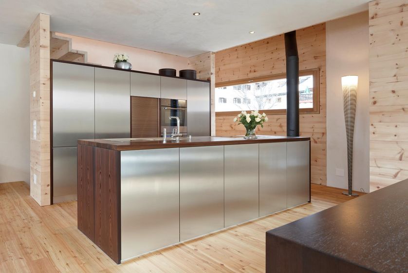 Moderner Holzkücheninnenraum mit Edelstahlgeräten und Holzverkleidung.