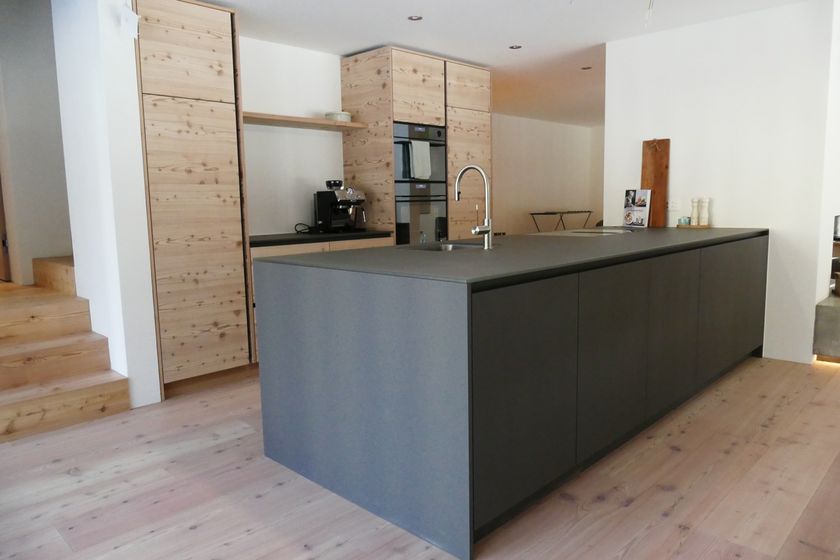 Moderne Küche mit Holzverkleidung und dunkelgrauer Insel.