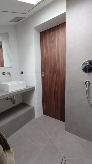 Modernes Badezimmer mit Holztür und Akustik-Wandbelägen.