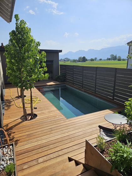 Moderne Holzterrasse mit Pool und Bergblick bei sonnigem Wetter.