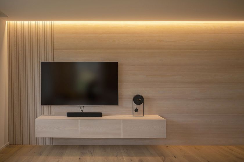 Modernes Wohnzimmer mit Holzverkleidung, Wand-TV und Soundsystem.