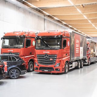 Rote Lkw der Stark AG in einem grossen Lager.
