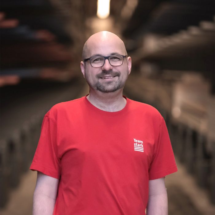 Mitarbeiter von Stark AG in Lagerhalle in rotem Shirt.