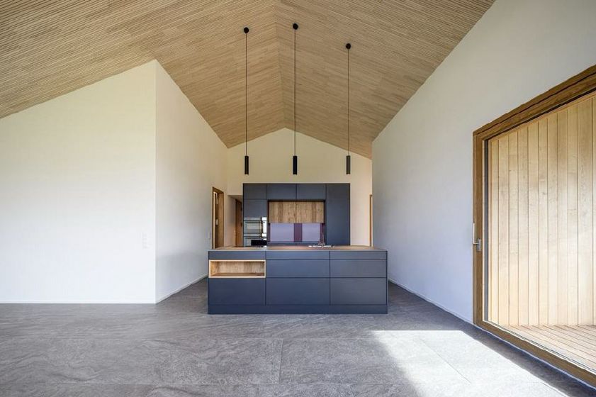 Moderne Küche mit Holz- und Dunkelgrauelementen in einem minimalistisch gestalteten Raum.